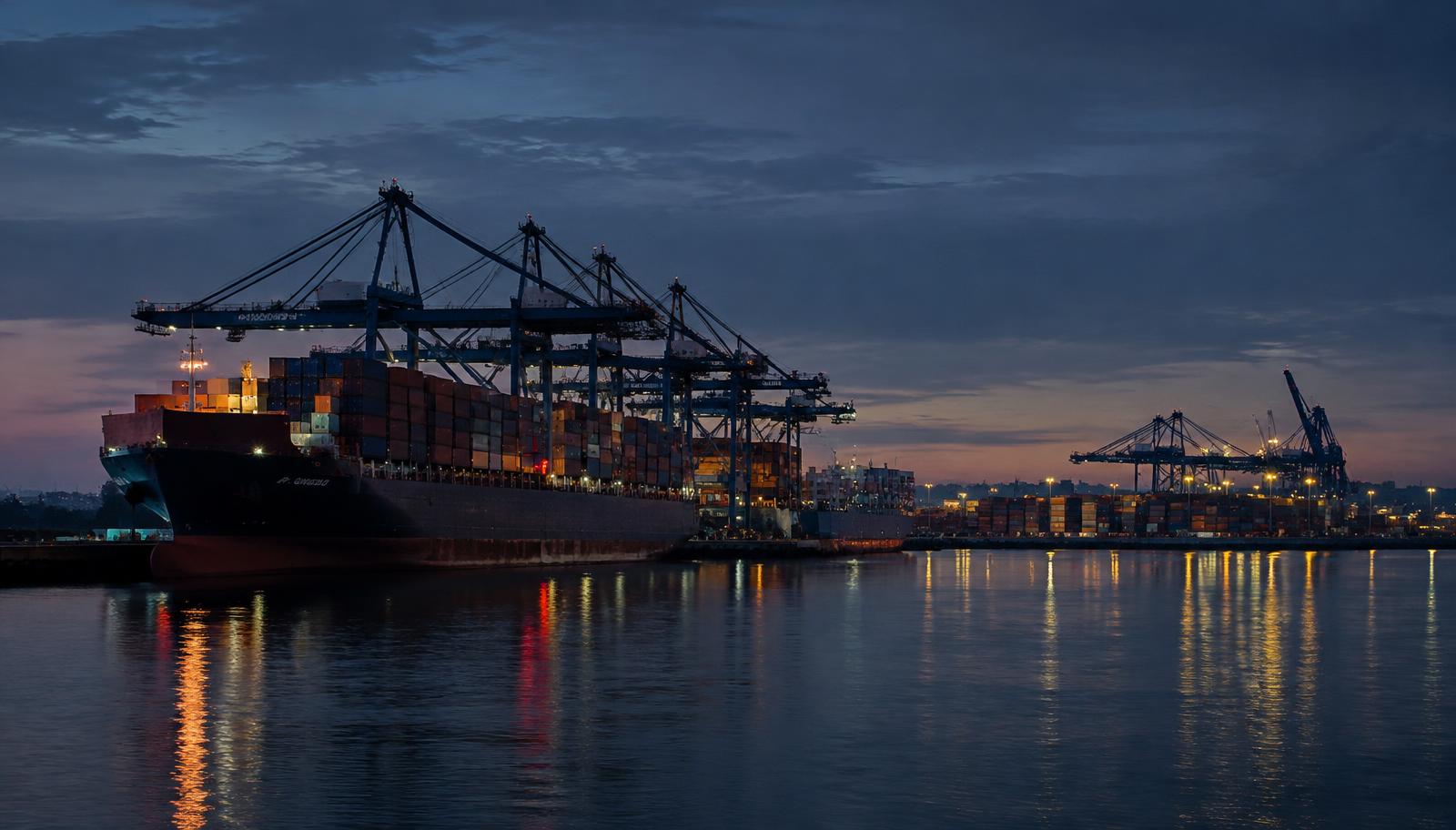 Container port at dusk with gantry cranes loading a cargo vessel